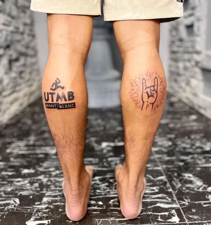 Lower leg tattoos featuring UTMB logo and a hand gesture in a vibrant design.