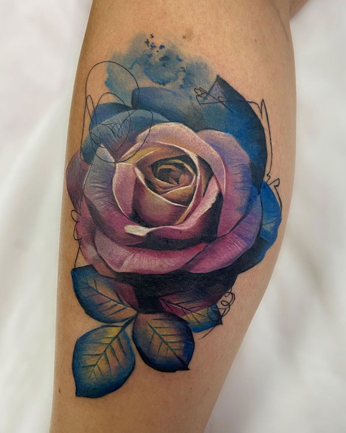 Colorful rose tattoo on lower leg, featuring rich purple and blue hues with green leaves.