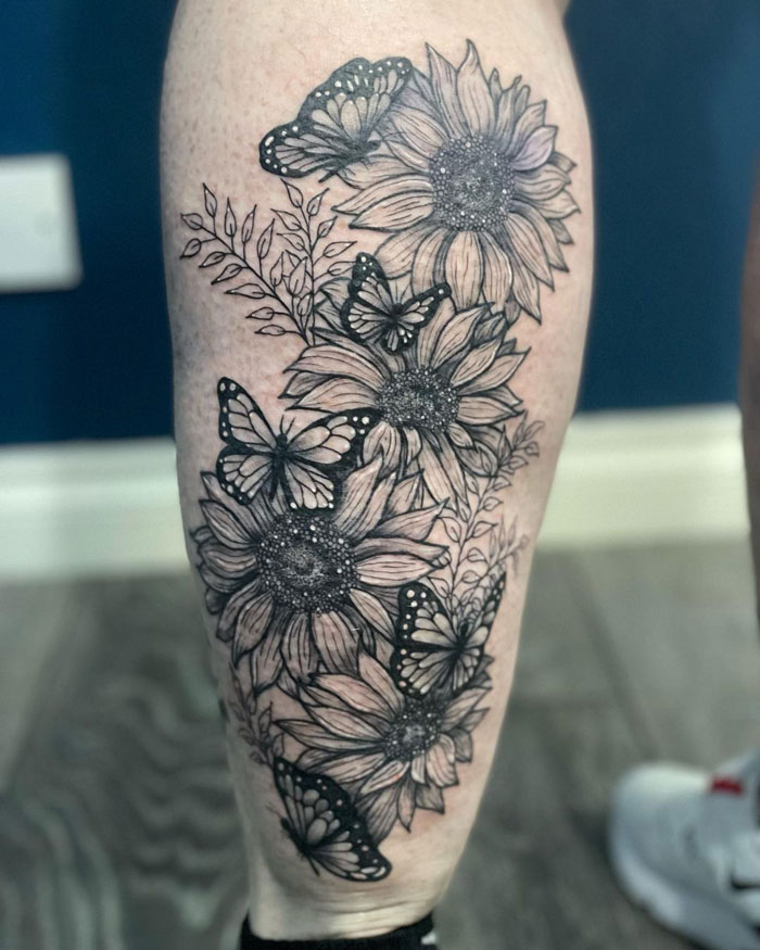 Calf tattoo with sunflowers and butterflies, showcasing a unique floral design.