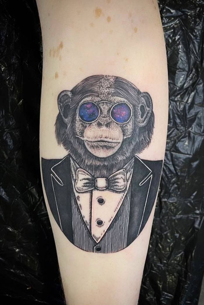 Calf tattoo of a chimpanzee in a tuxedo with galaxy glasses, showcasing unique and cool design ideas.