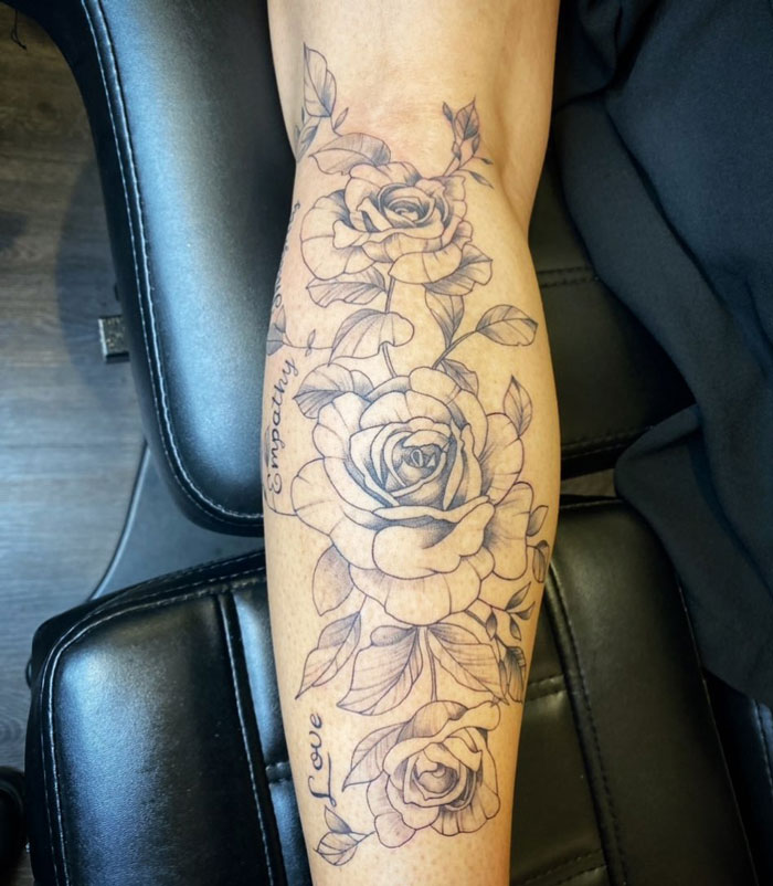 Lower leg tattoo of detailed roses with "Empathy" and "Love" text on the calf.