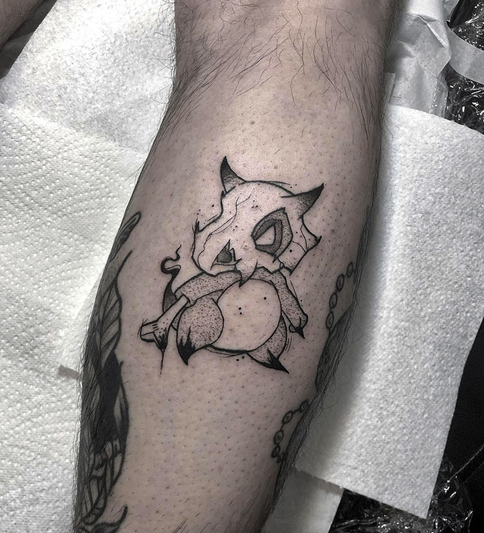 Unique calf tattoo featuring a stylized cartoon character design in black ink.