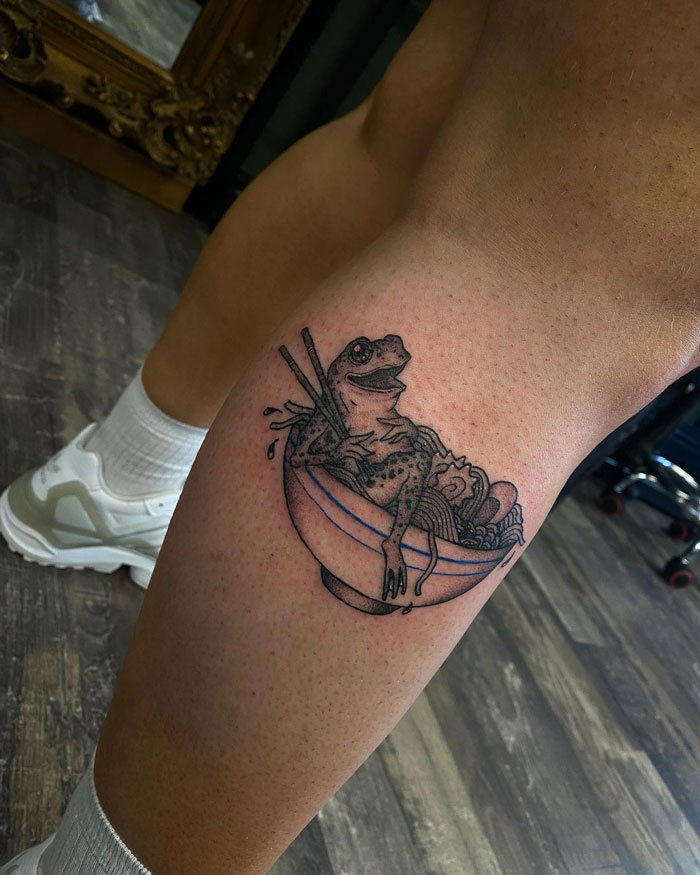 Frog in ramen bowl tattoo on calf, showcasing a unique calf tattoo idea in a tattoo studio.