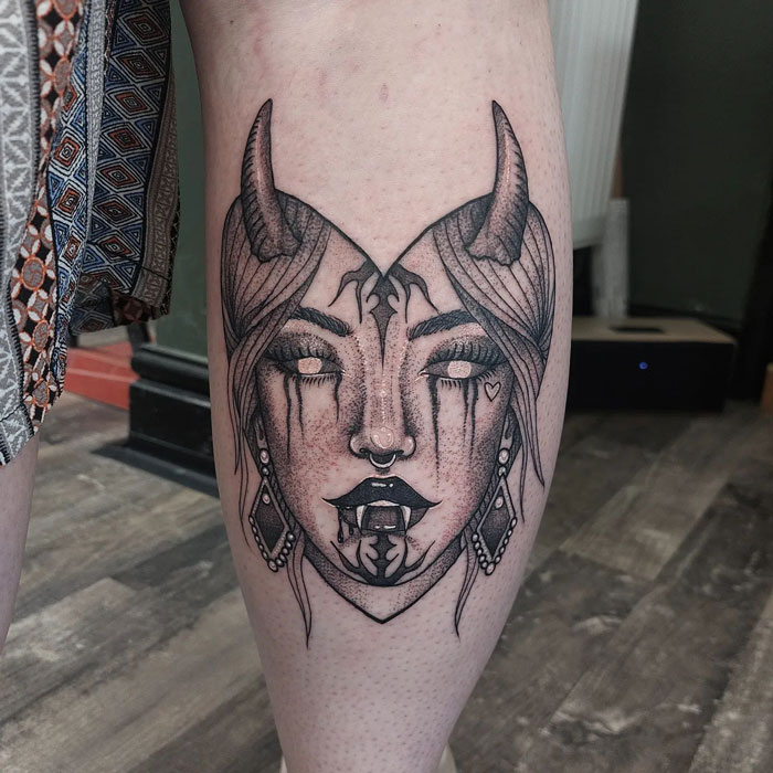 Demon-inspired calf tattoo showcasing intricate linework and shading.