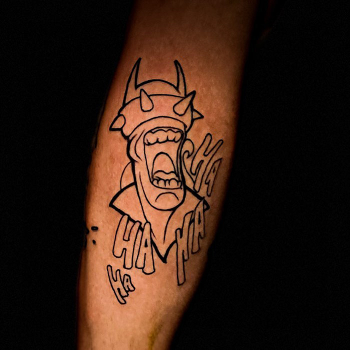 Unique calf tattoo featuring a horned character laughing with "Ha Ha Ha" text in bold black lines.
