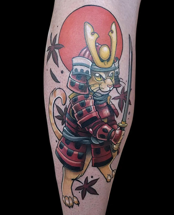 Samurai cat tattoo on calf, showcasing coolness with red armor and sword.