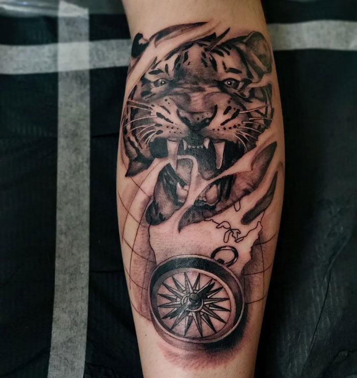 Tiger and compass design on calf tattoo, showcasing intricate details and bold lines.