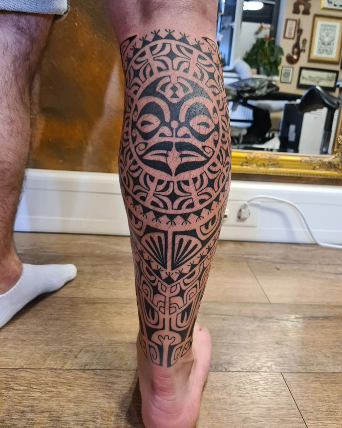 Tribal-style calf tattoo featuring intricate patterns and bold lines, showcasing unique tattoo art.