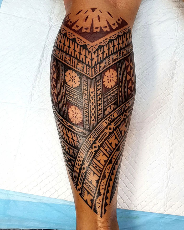 Intricate lower leg tattoo featuring geometric and floral patterns.