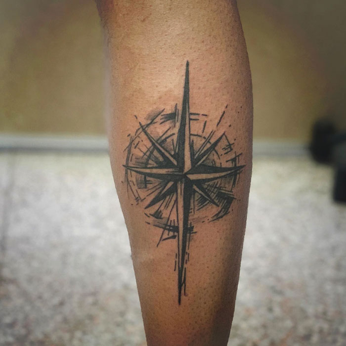 Unique calf tattoo featuring a black compass design.