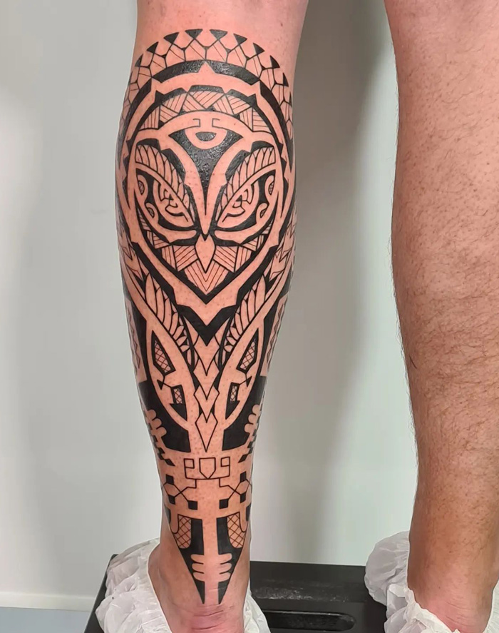Geometric tribal calf tattoo featuring bold black lines and intricate patterns.