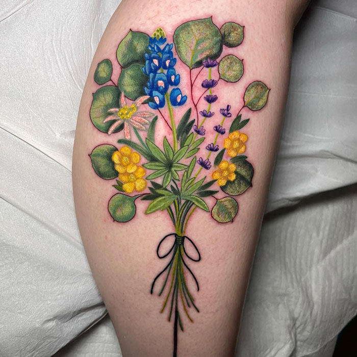 Floral calf tattoo featuring colorful flowers and greenery, showcasing artistic coolness.
