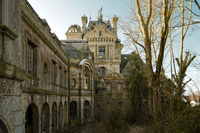 Abandoned castle with weathered stone walls and overgrown vegetation under a clear sky during daytime worldwide exploration.