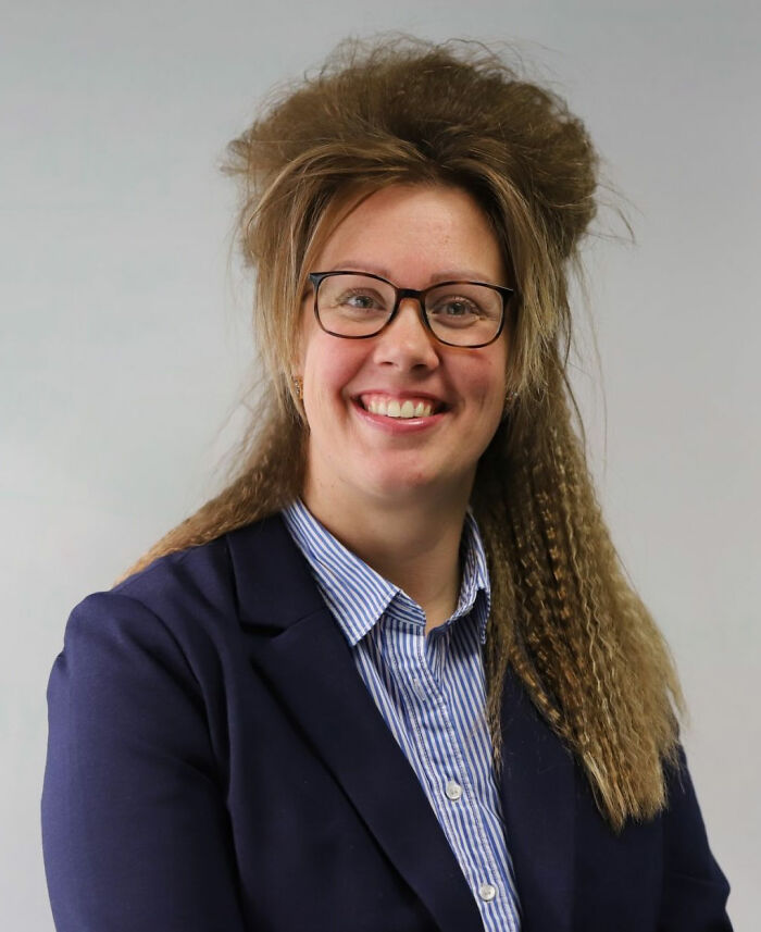 Person smiling with a unique and unconventional hairstyle, wearing glasses and a suit jacket, showcasing a bad haircut idea.