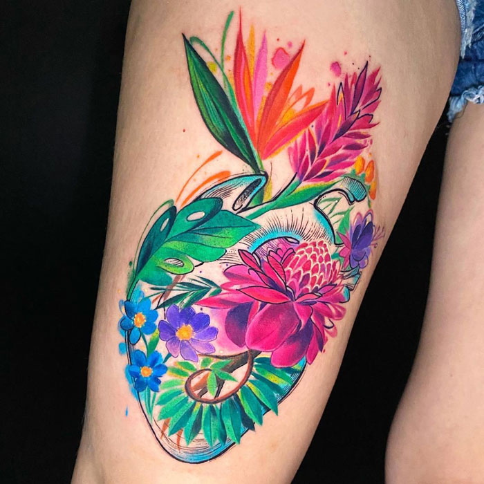 Colorful watercolor tattoo featuring vibrant flowers and leaves.