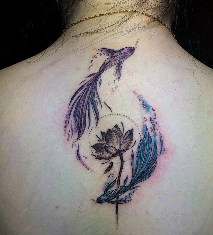 Ethereal watercolor tattoo of koi fish and lotus on a back, showcasing fluid colors and delicate design.