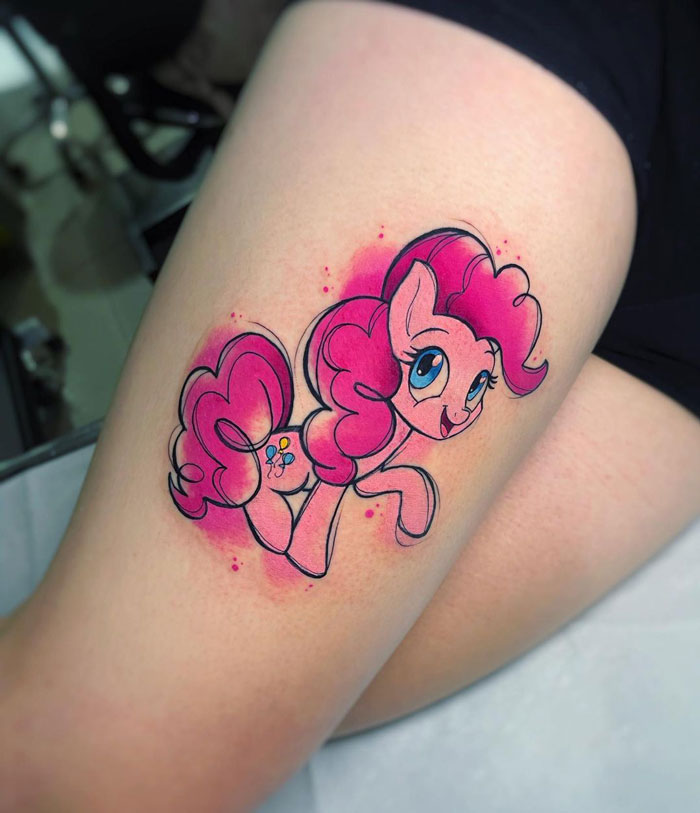 Vibrant pink watercolor tattoo of a cartoon pony on the thigh, showcasing inkspiration.