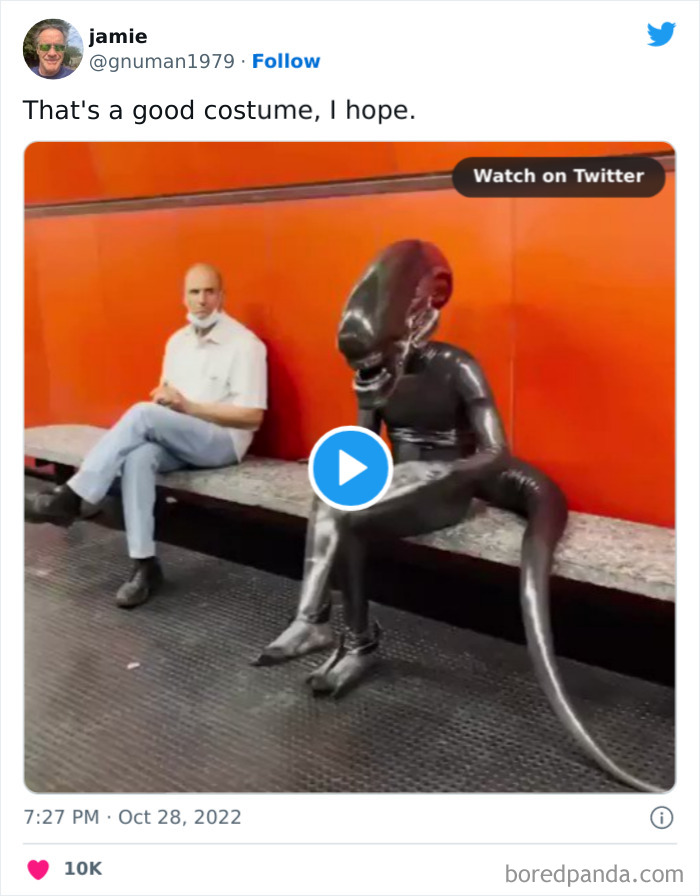 Person in a detailed alien costume sitting on a bench at a subway station, showcasing Halloween costume creativity.