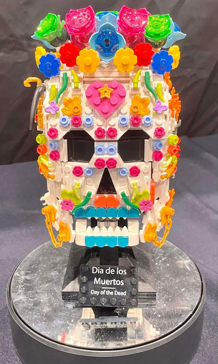 Intricate LEGO builds featuring a colorful Day of the Dead skull decorated with flowers and vibrant details on display.