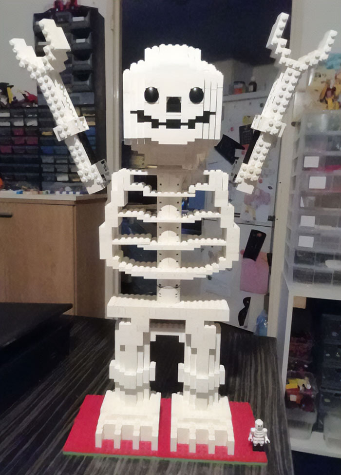 Large white LEGO skeleton build with raised arms and a small skeleton figure, showcasing incredible LEGO builds artistry.
