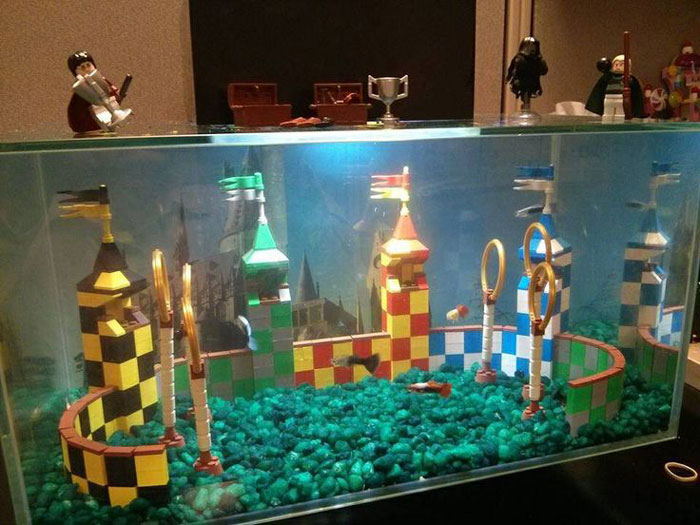 Colorful LEGO builds resembling a Quidditch stadium with towers, rings, and flags displayed inside a glass case.