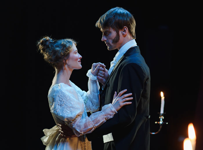Couple in period costumes sharing an intimate dance, illuminated by candlelight, capturing a fun activity at home.