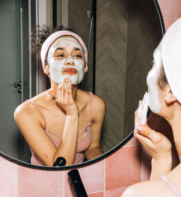 Woman applying a face mask at home, enjoying a fun skincare routine to avoid boredom.