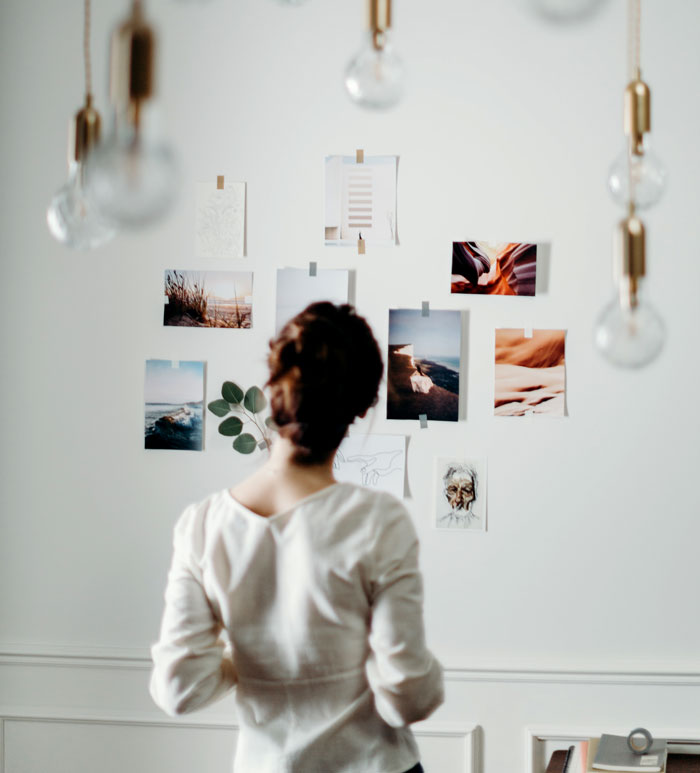 Woman creating a photo wall at home, surrounded by artistic images.
