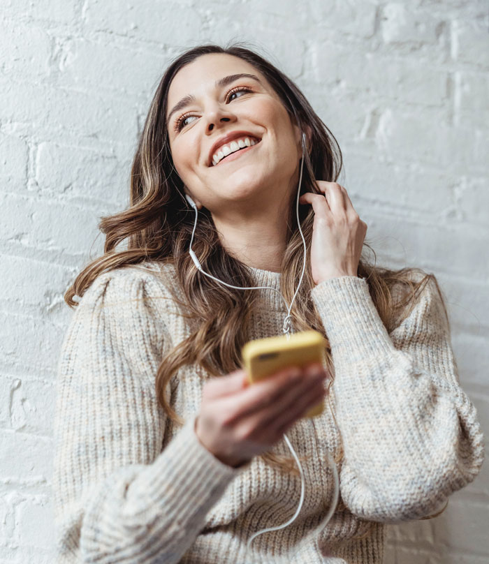 Smiling woman with headphones enjoying music at home, avoiding boredom.