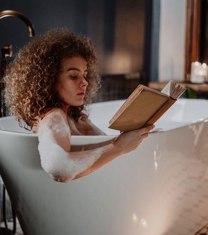 Person reading in a bubble bath, surrounded by cozy ambiance, enjoying fun things to do at home.