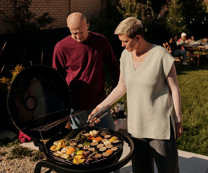 Couple grilling vegetables outdoors as a fun activity to do at home.