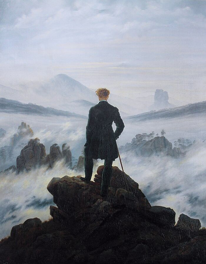 A figure stands atop a rocky cliff, overlooking a foggy landscape, embodying classic landscape painting style.