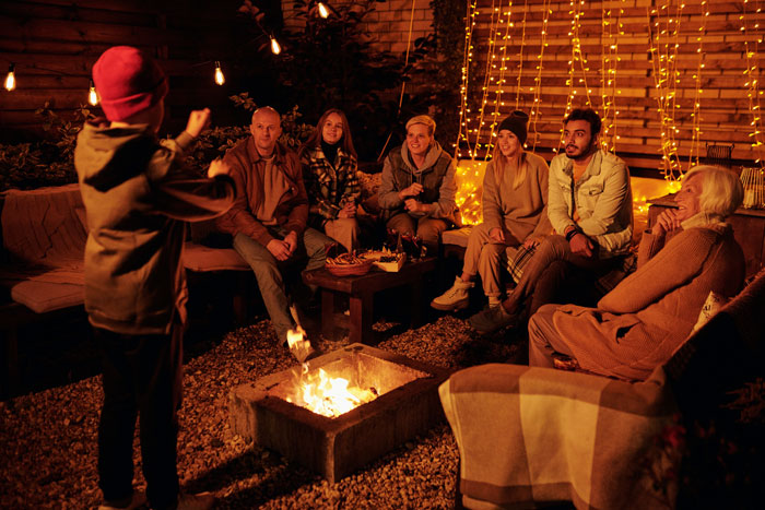 Group enjoying a cozy evening at home around a fire pit, avoiding boredom with fun activities.
