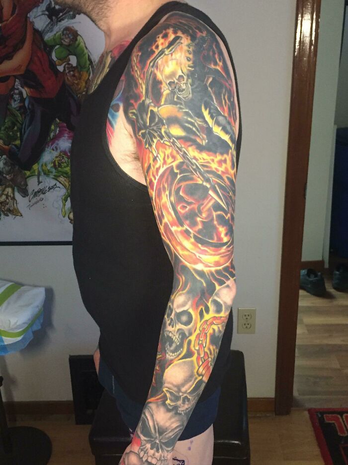 Person with a detailed Marvel-themed arm tattoo featuring a flaming skull in vibrant colors.
