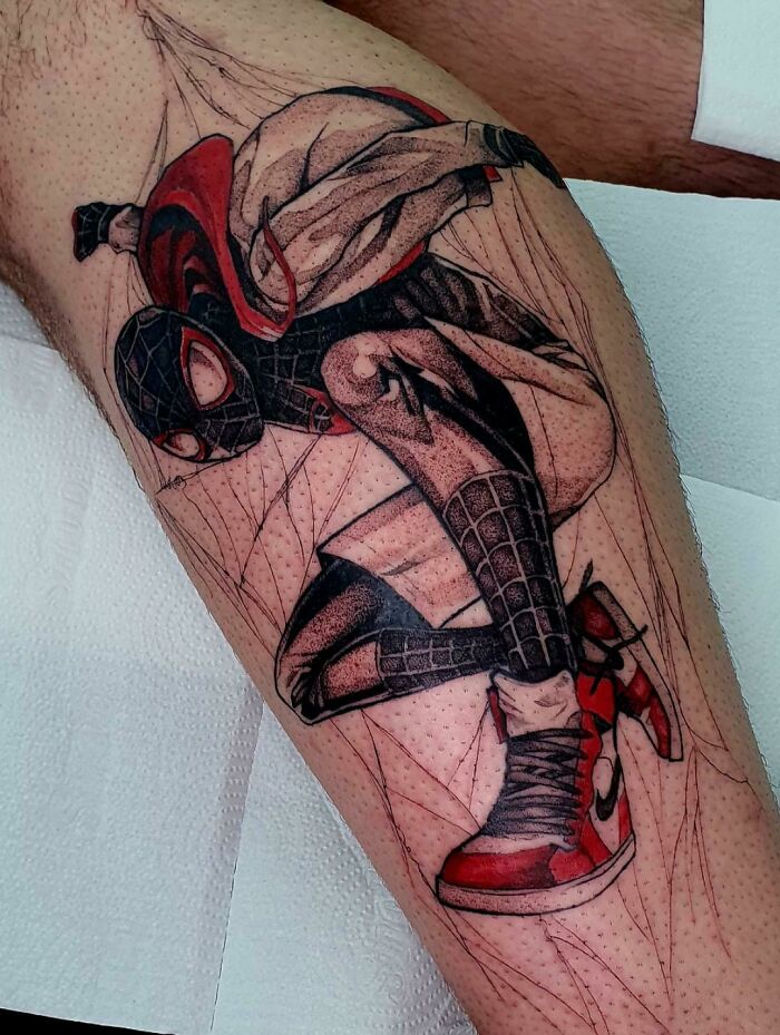 Marvel tattoo of a superhero in action with a detailed costume and red sneakers on a person’s leg.