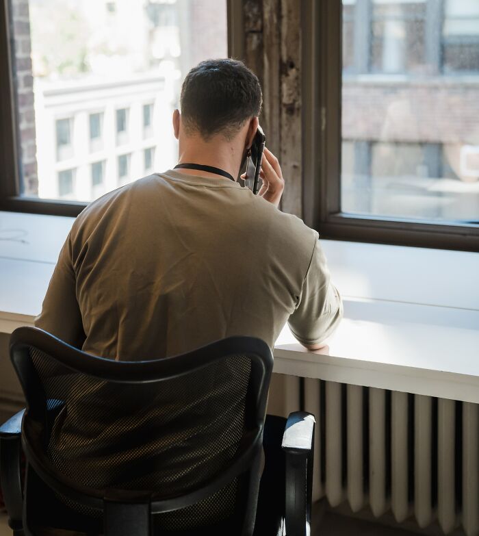 Man Calling Someone On The Phone In Front Of The Window