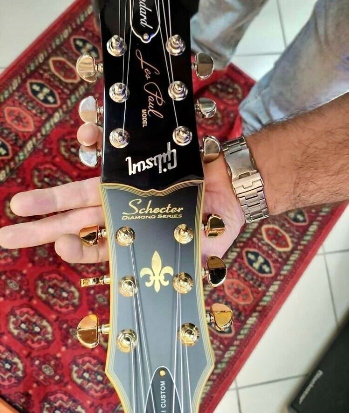 The Heads Of A Gibson Guitar And A Schecter Guitar Perfectly Fitting Together