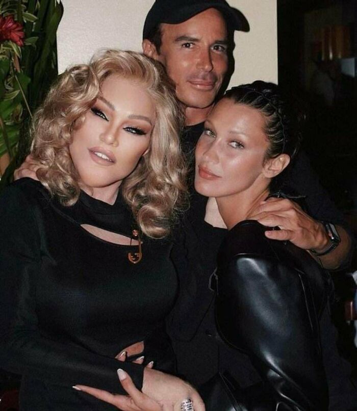 Three people posing together indoors with one person wearing dramatic makeup and styled hair, showcasing Instagram reality.