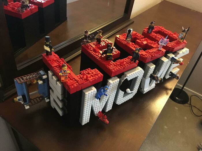LEGO builds spelling LEGO with mini figures on top displayed on a wooden surface, showcasing incredible LEGO builds art.