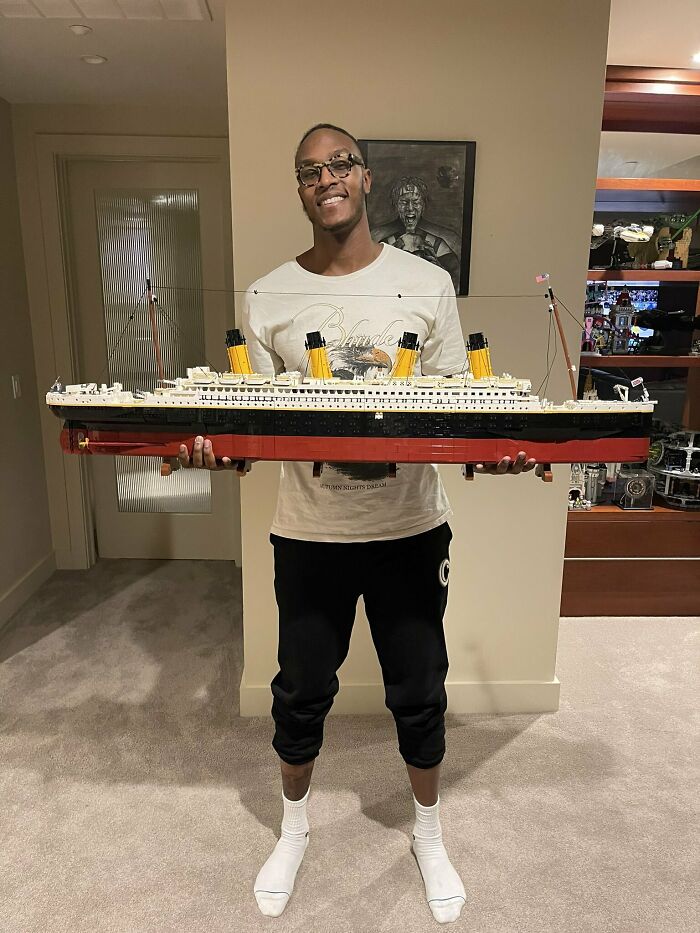 Man holding an incredible LEGO build of a detailed ship model, showcasing one of the most impressive LEGO builds.