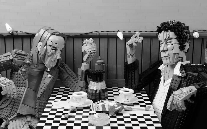 Two detailed LEGO builds depict people having coffee at a checkered table, showcasing incredible LEGO art craftsmanship.