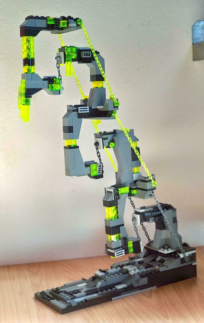 Intricate LEGO build featuring gray and neon green pieces forming an abstract art structure on a wooden table.