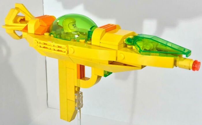 Yellow and green incredible LEGO build of a futuristic spaceship with a minifigure pilot inside cockpit.