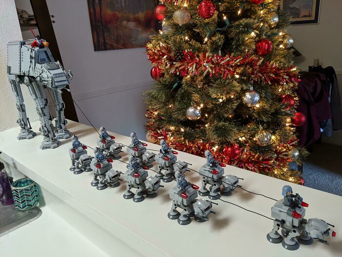 Intricate LEGO builds of Star Wars walkers and soldiers displayed on a table in front of a decorated Christmas tree.