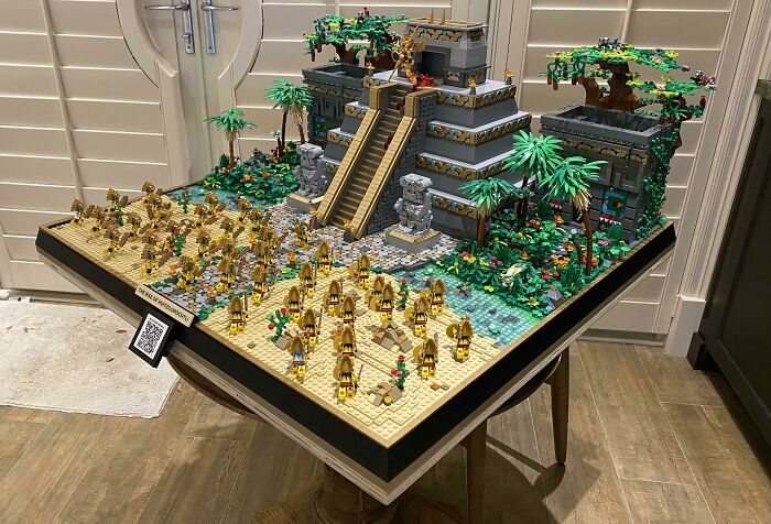 Intricate LEGO builds depicting an ancient temple with surrounding jungle and numerous detailed minifigures on display.