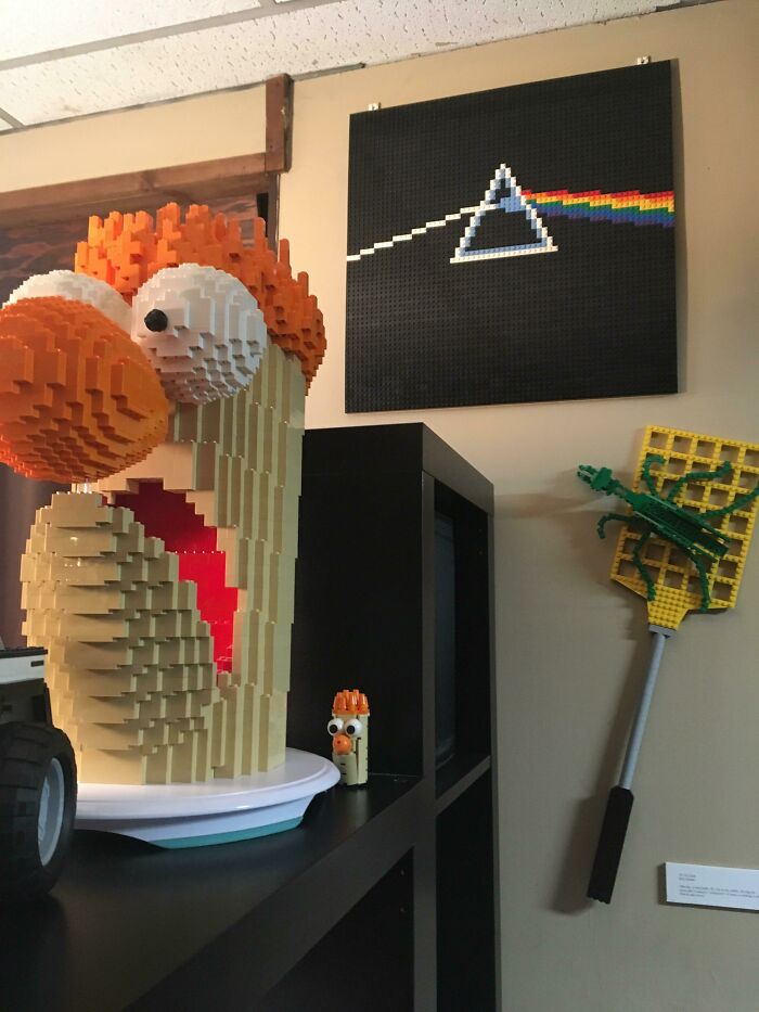 Large detailed LEGO build of Animal from the Muppets with wall art and a LEGO flyswatter displayed indoors.