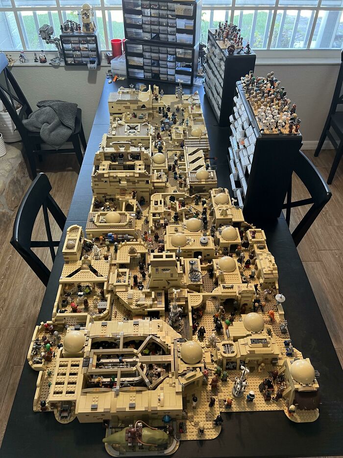Large, detailed LEGO build of a desert city with numerous minifigures and storage drawers in the background.