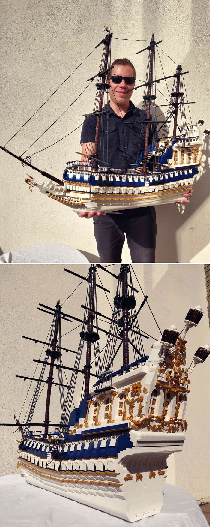 A man holding an incredible LEGO build of a detailed blue and white sailing ship with intricate rigging and decorations.