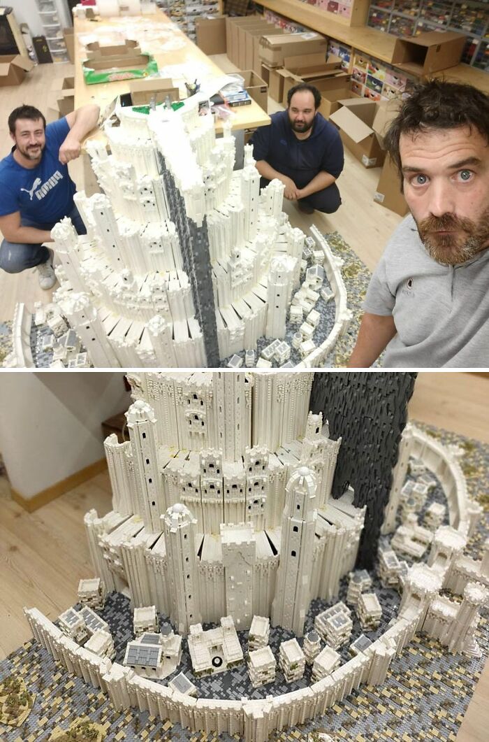 Three men posing with a detailed white LEGO build showcasing an intricate castle structure and surrounding walls.