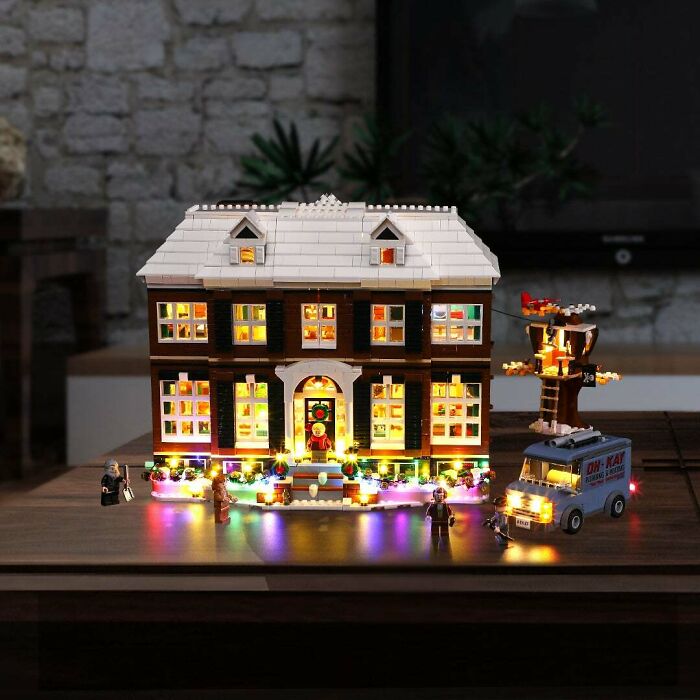 Detailed LEGO build of a lit-up house with minifigures and a van, showcasing incredible LEGO art and creativity.